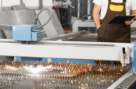 Engineer observing plasma laser cutting metal sheet.